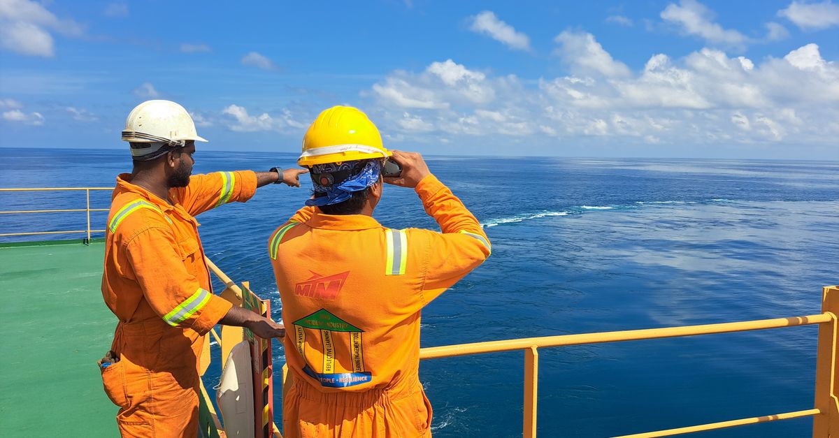 Marine workers on a ship deck looking out to sea
